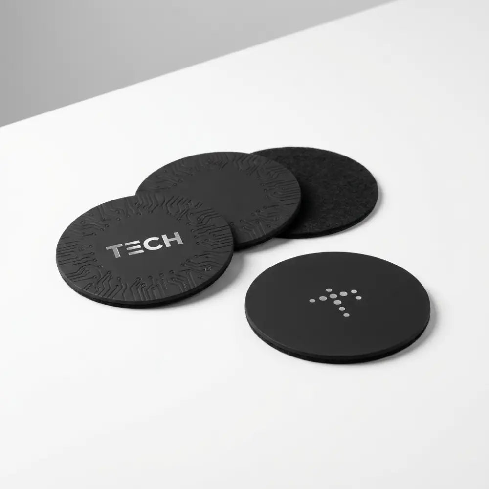 Black coasters with 'TECH' branding on a white surface