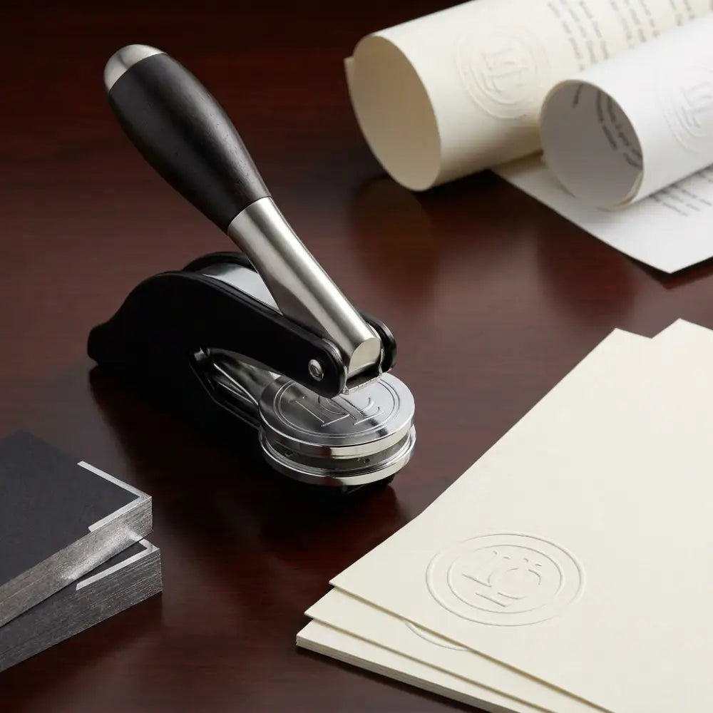 Stamp with a wooden handle on a desk with stamped paper and ink pad.