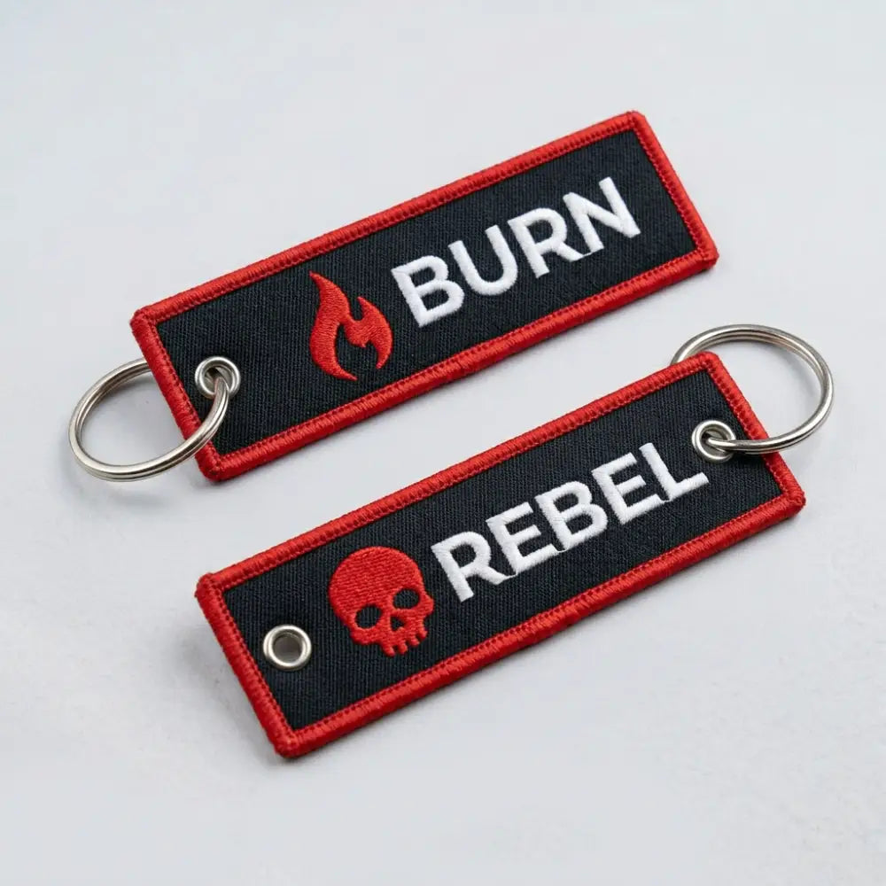 Two keychains with 'BURN' and 'REBEL' text on a light gray background