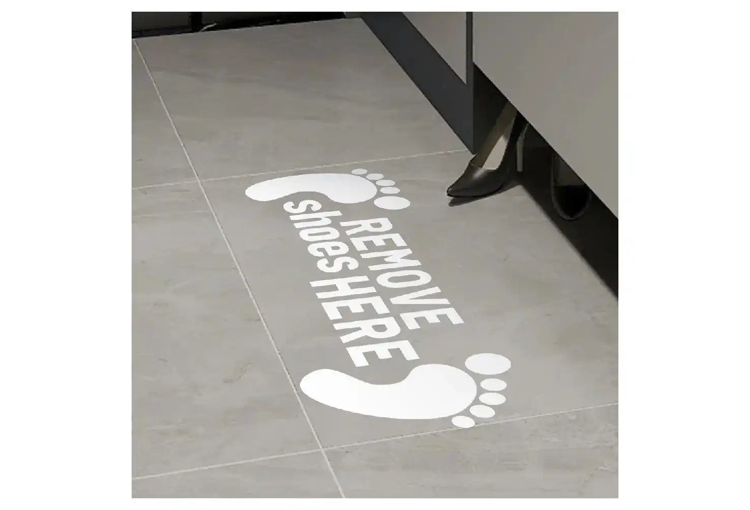 White footprint decals on a floor with text that reads ’REMOVE SHOES HERE’